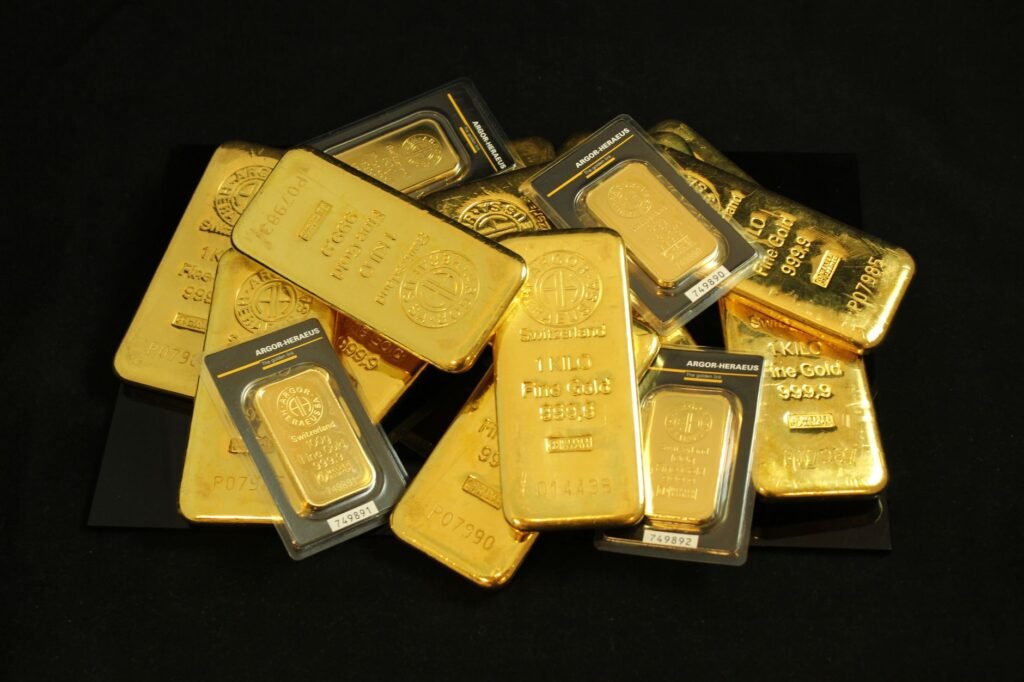 Pile of gold bars in assorted sizes, some in sealed packaging, on a black background