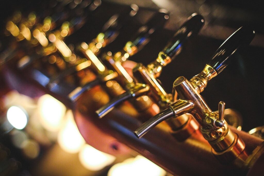 Row of polished brass draft taps glowing under warm bar lighting