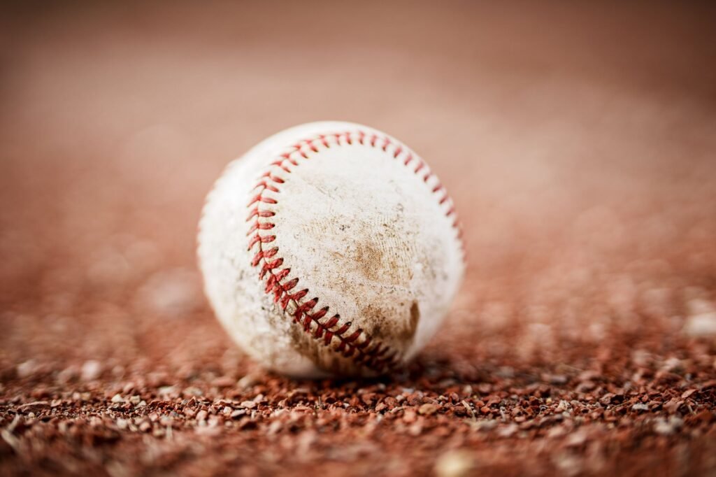 Scuffed baseball resting on red infield dirt