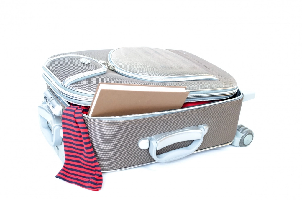 Packed carry on suitcase open on a bed