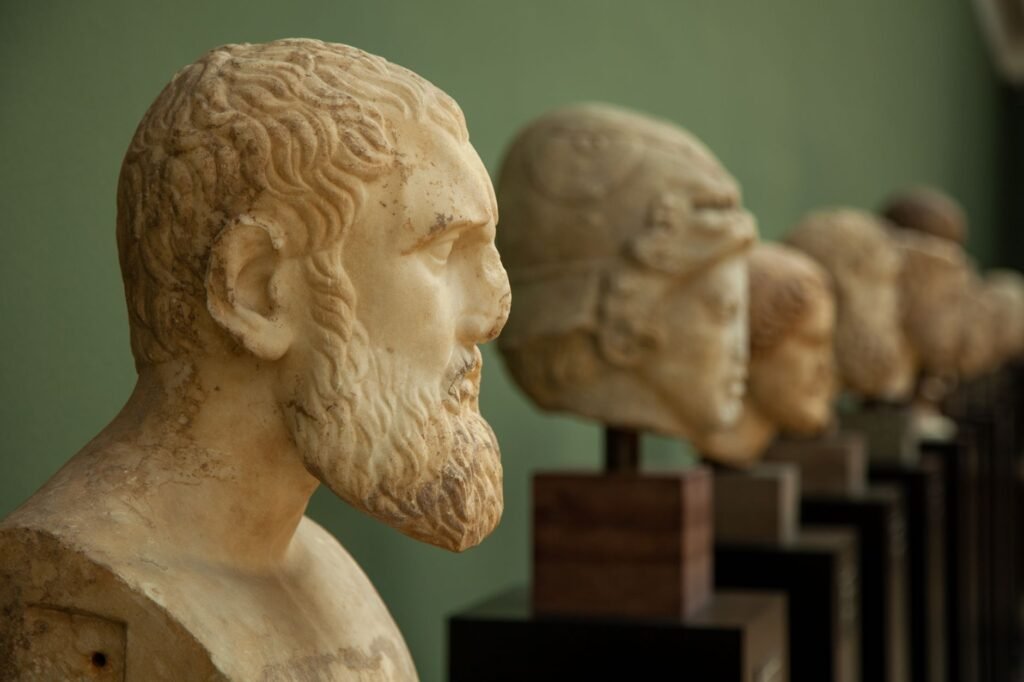 Carved stone bust of a bearded man in profile with a row of busts along a green wall