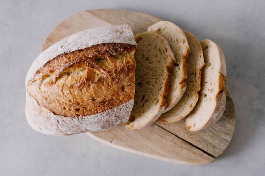 Freshly sliced artisan bread on a rustic wooden board, perfect for food blogs and cookbooks