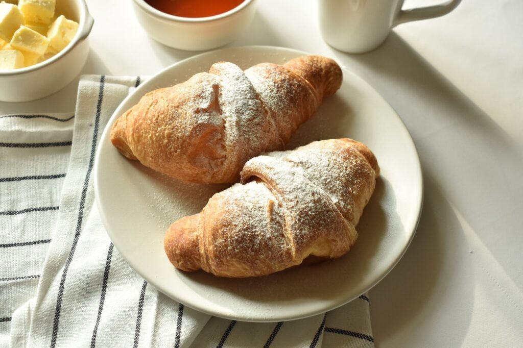 Tasty croissants served with butter and coffee on a bright morning