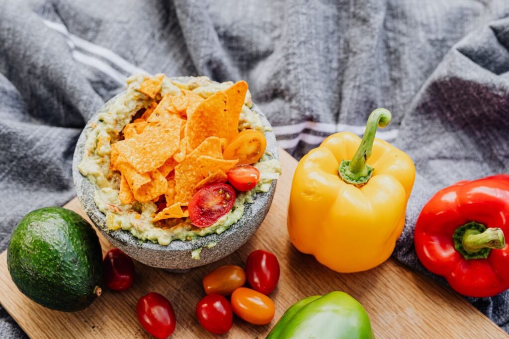 Delicious guacamole with nachos served with fresh bell peppers and cherry tomatoes.
