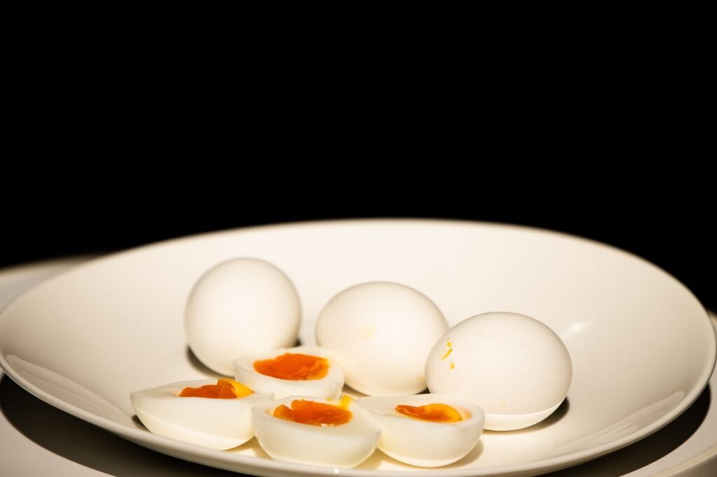 A white plate of hard-boiled eggs, some sliced, against a dark background
