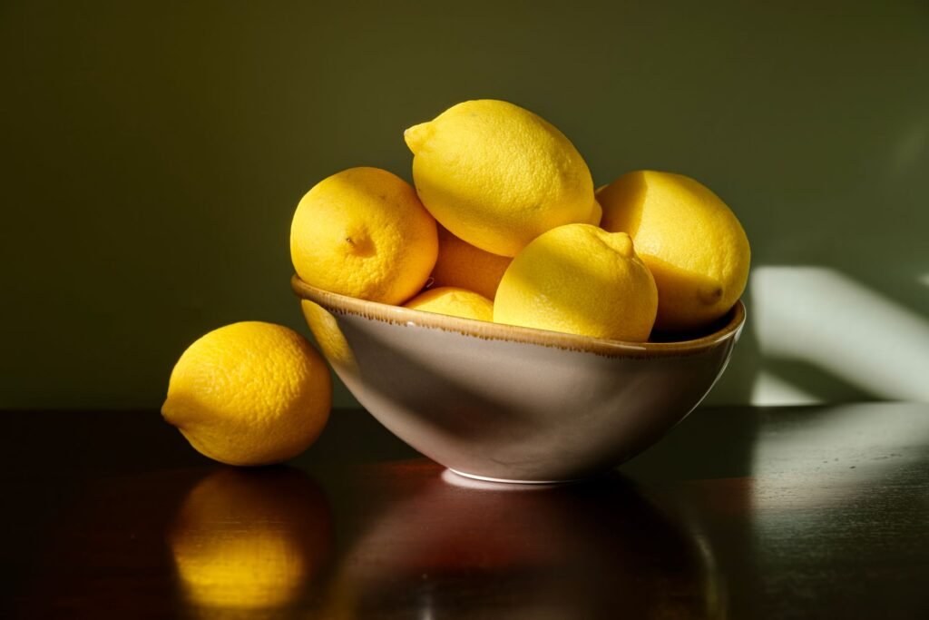 A vibrant arrangement of fresh lemons in a ceramic bowl, bathed in soft morning light, creating an inviting...