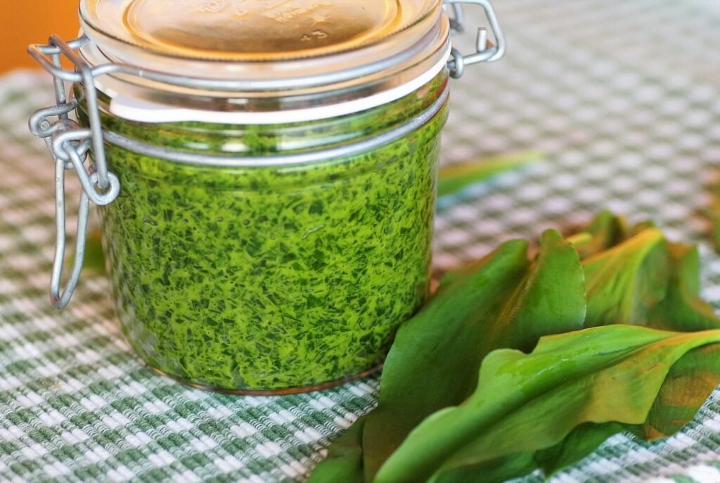 Jar of green pesto with a spoon
