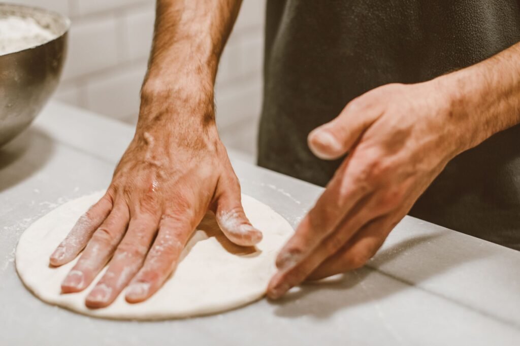 Close-up of hands shaping pizza dough, capturing the art of cooking