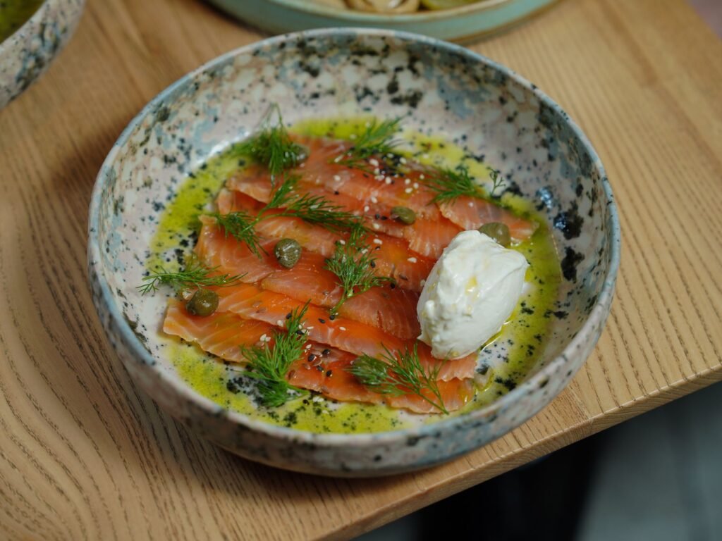 Appetizing smoked salmon with mozzarella cheese, dill, capers, and olive oil in a ceramic dish