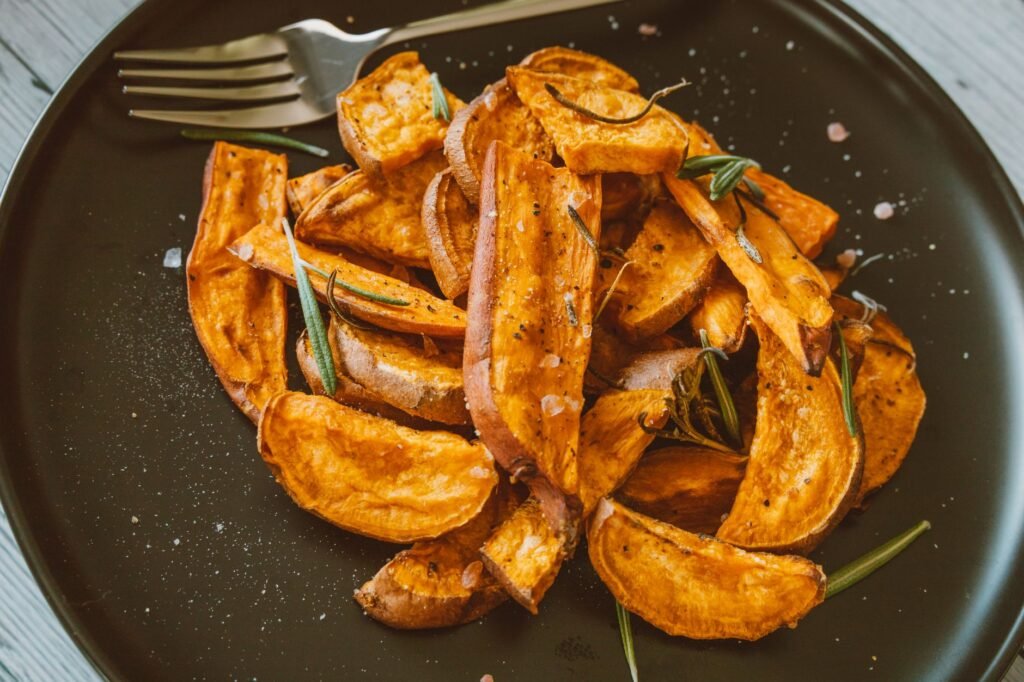 Close-up of crispy sweet potato wedges topped with rosemary, perfect for a healthy snack