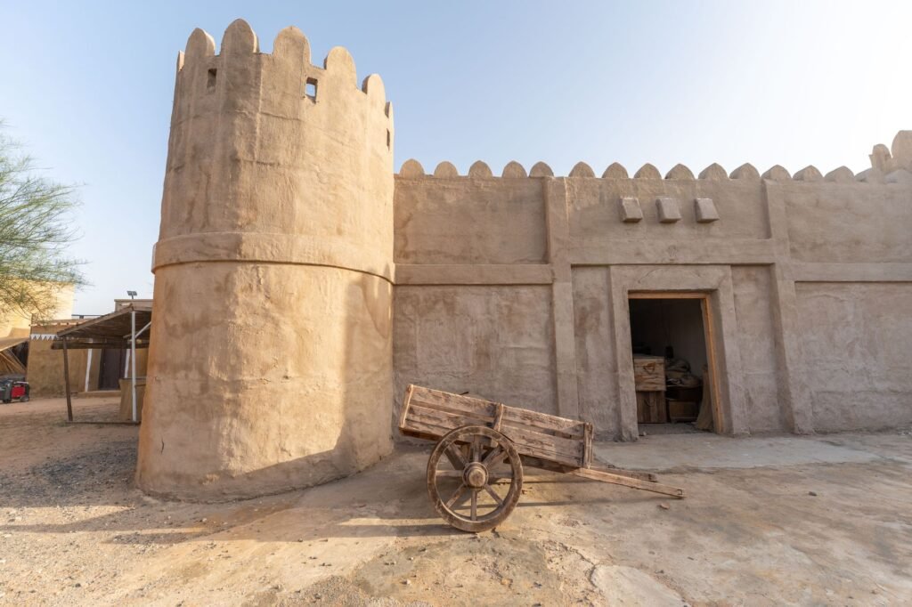 Rustic sand-colored fortress featuring an old wooden trolley under a clear sky