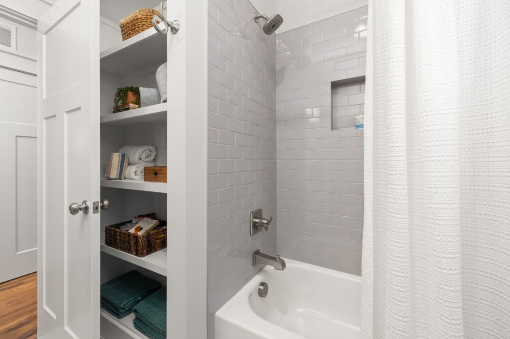Bright and clean modern bathroom with gray tiles, shower, and organized shelving