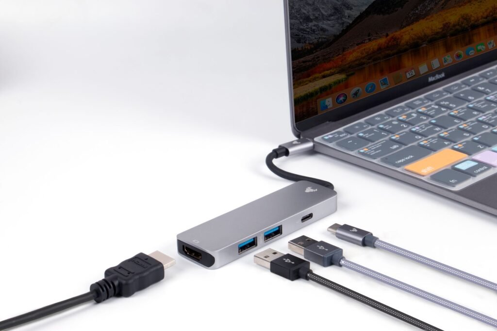 Close-up view of a USB hub connected to a laptop, showcasing various ports and cables on a white surface