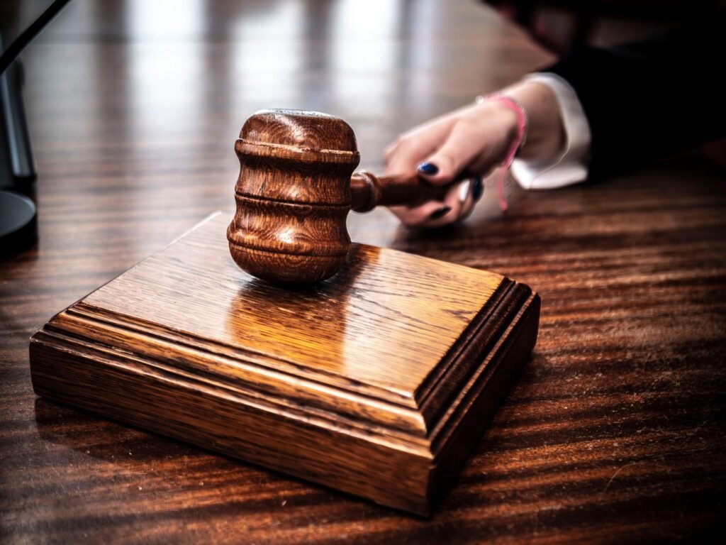 Polished wooden gavel resting on its sound block on a glossy wooden desk