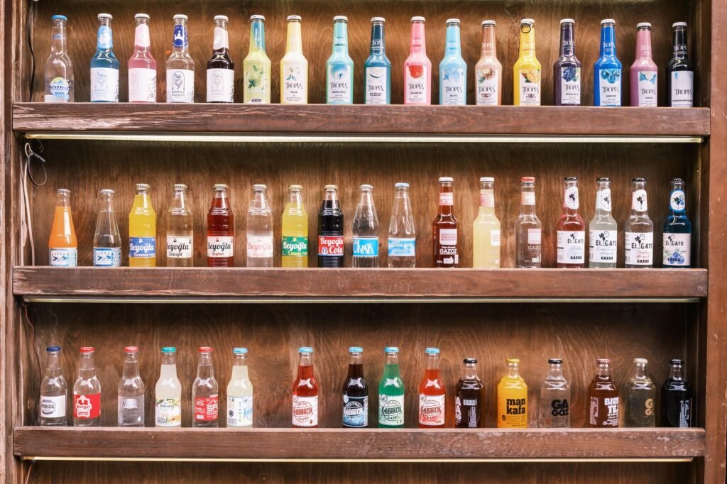 A vibrant collection of vintage soda bottles displayed on wooden shelves, showcasing diverse colors and labels