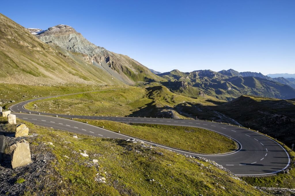 A winding road through picturesque mountain landscape under a clear blue sky
