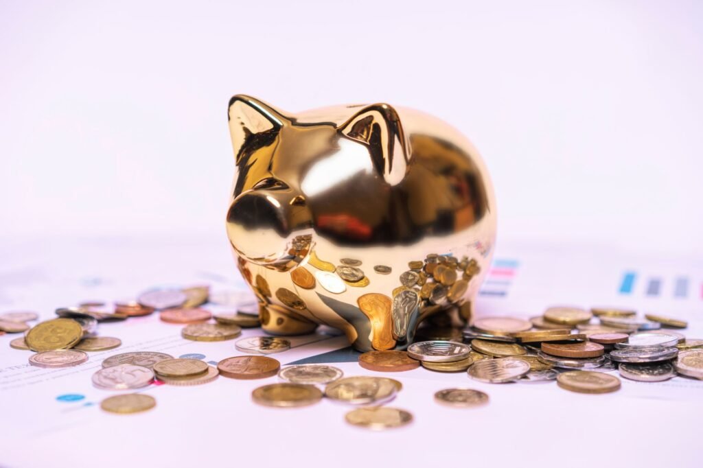 Shiny golden piggy bank on financial documents with scattered coins symbolizes savings