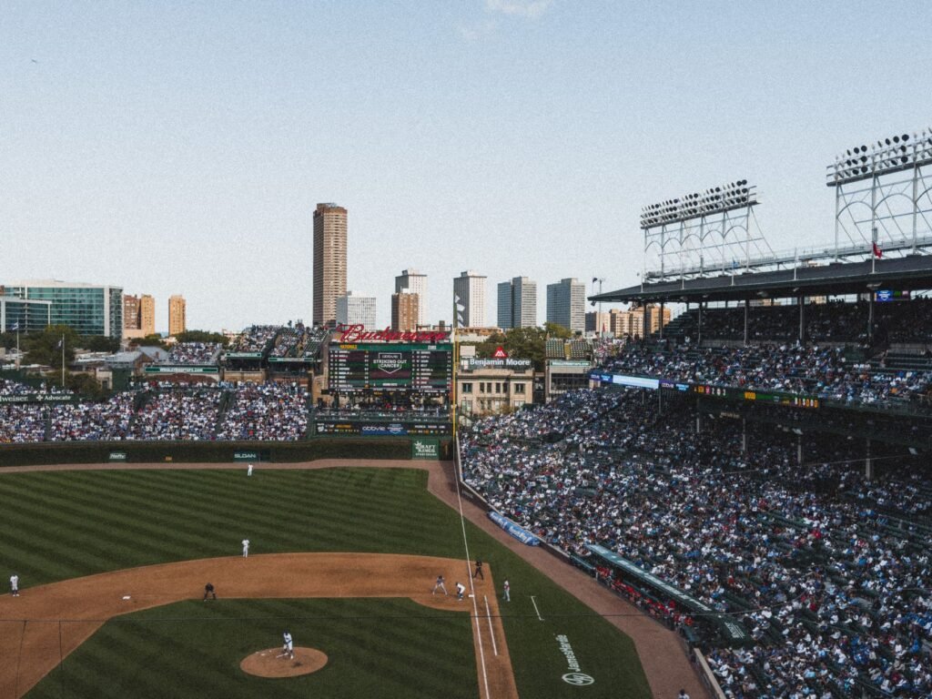 Crowded baseball stadium under a clear sky with cityscape background. Energetic game day atmosphere.