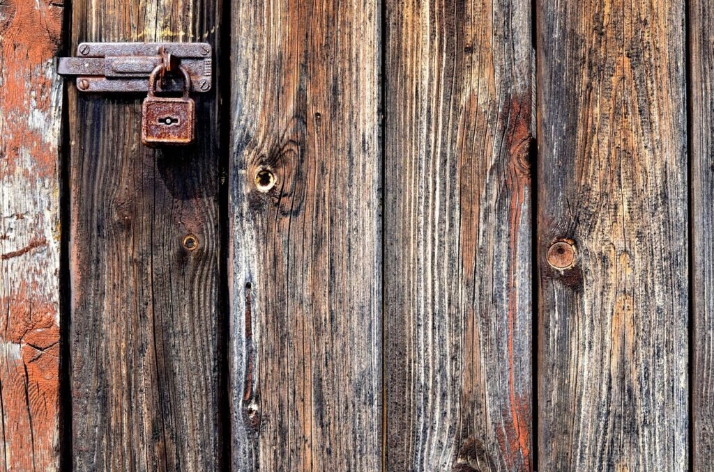 A metal hasp and padlock fastening a red barn door