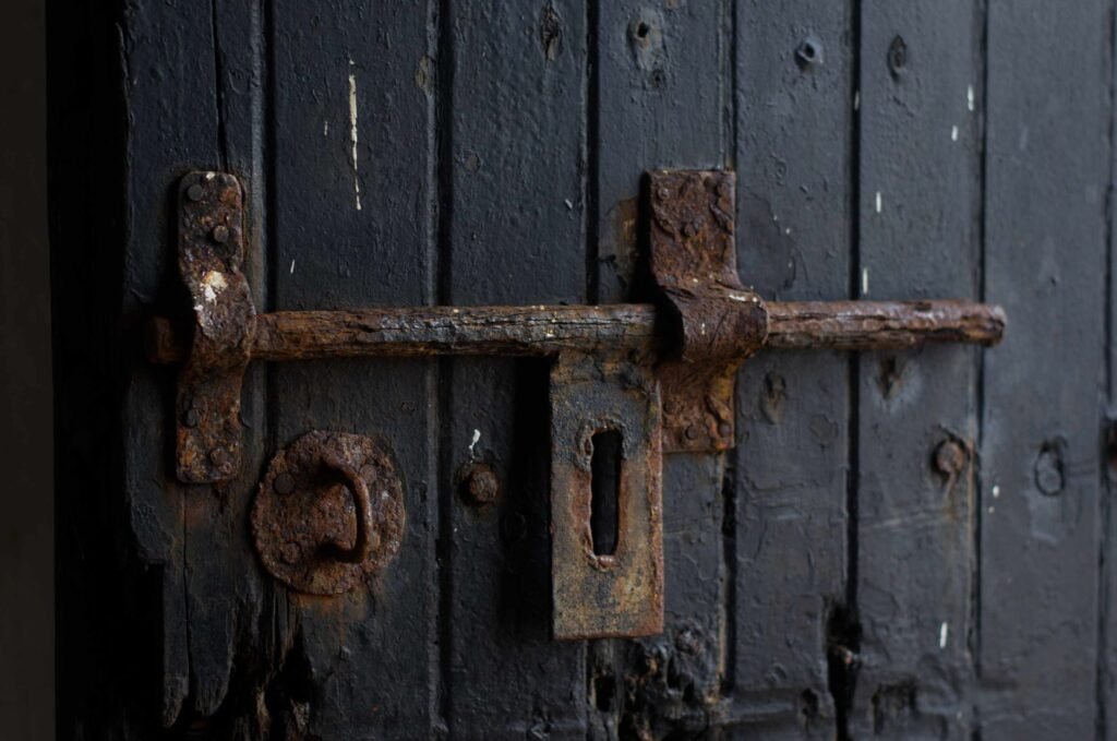 Rusty lock on a weathered wooden door, depicting age and decay
