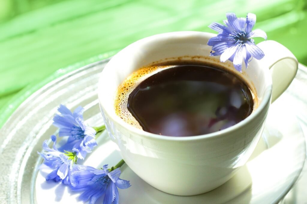 Cup of dark black coffee on a glass saucer with pale blue flowers beside it