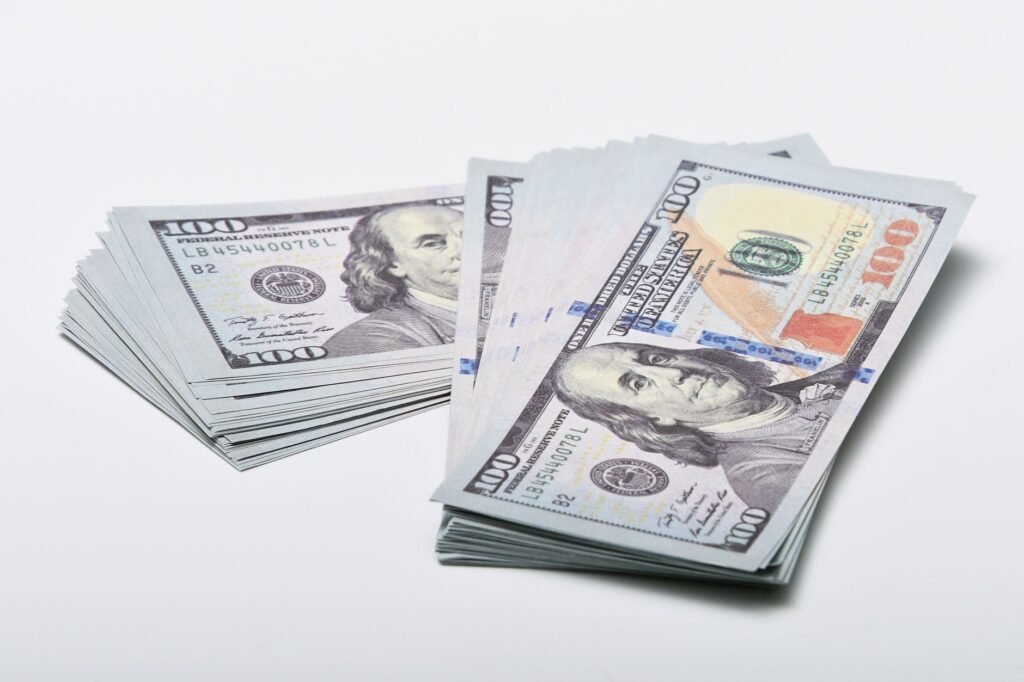 Two stacks of hundred dollar bills fanned out on a plain white surface