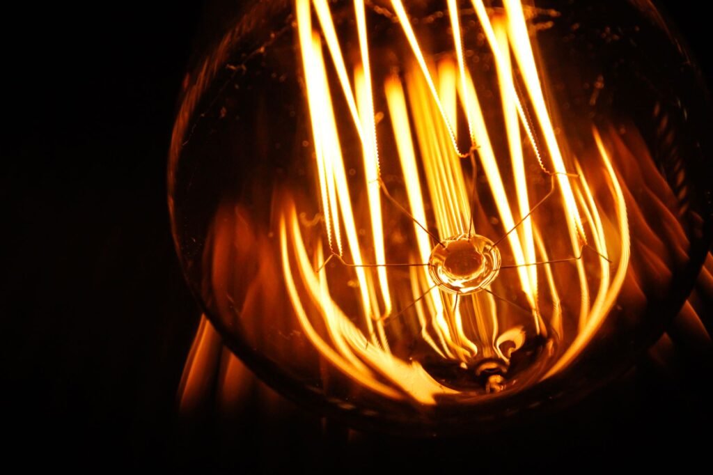 Close-up shot of illuminated light bulb filaments creating a warm glow and abstract pattern