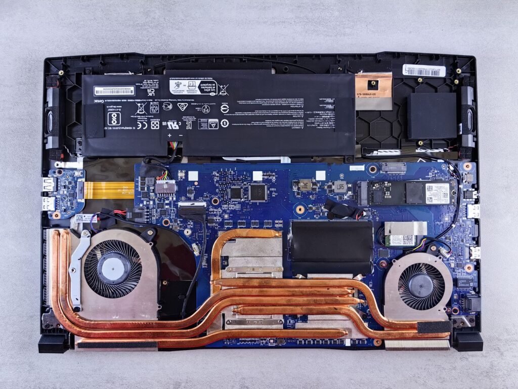 The inside of an opened laptop showing the motherboard, battery and cooling fans