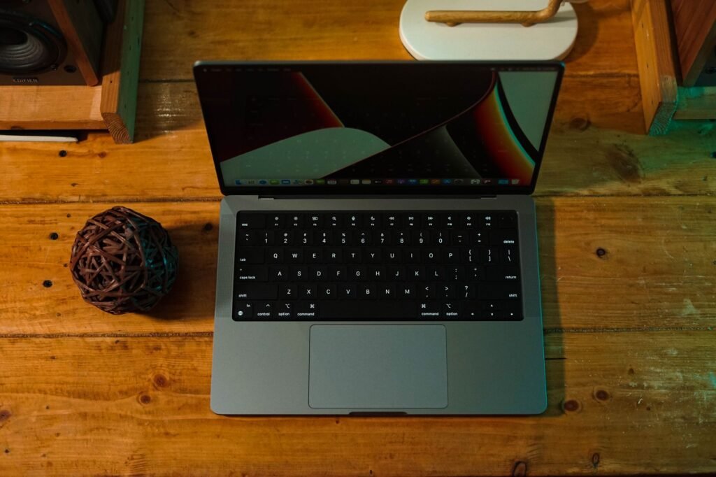 A sleek laptop on a wooden desk, featuring tech and decor elements