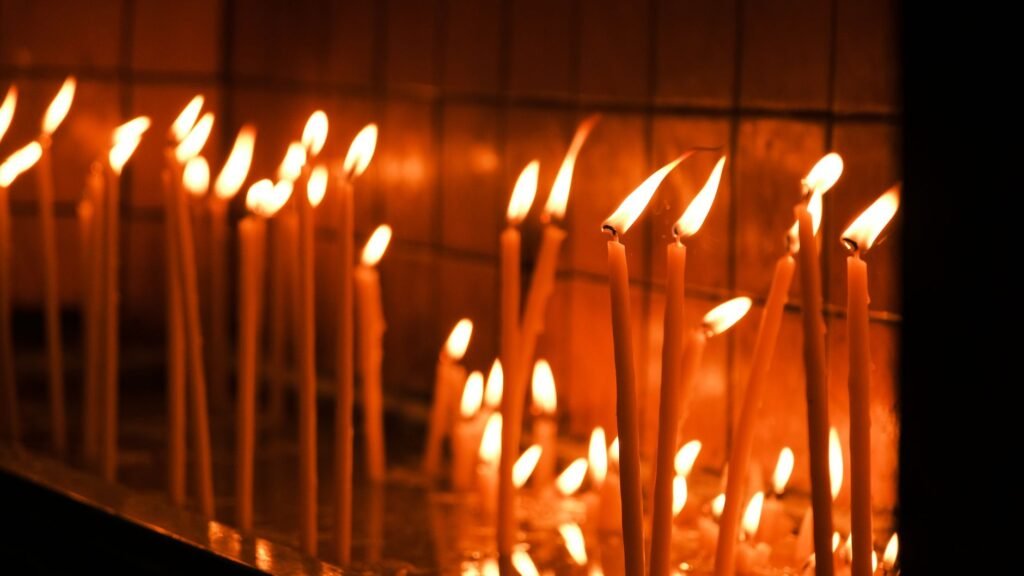 A serene image of tall candles glowing warmly in a dimly lit room, creating a peaceful ambience