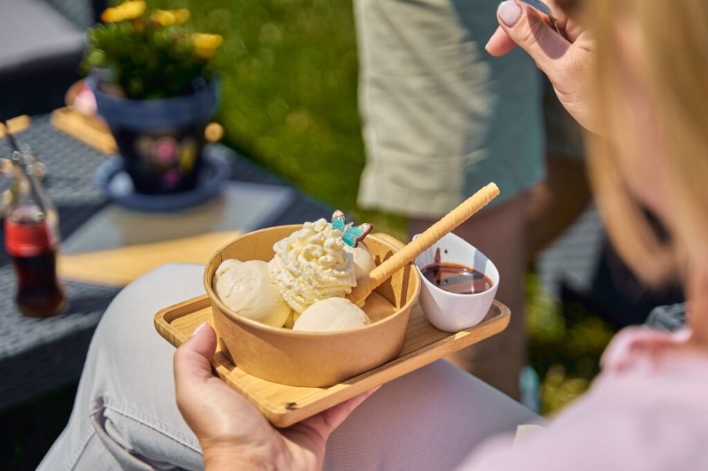 Indulge in creamy ice cream with whipped cream and chocolate sauce outdoors