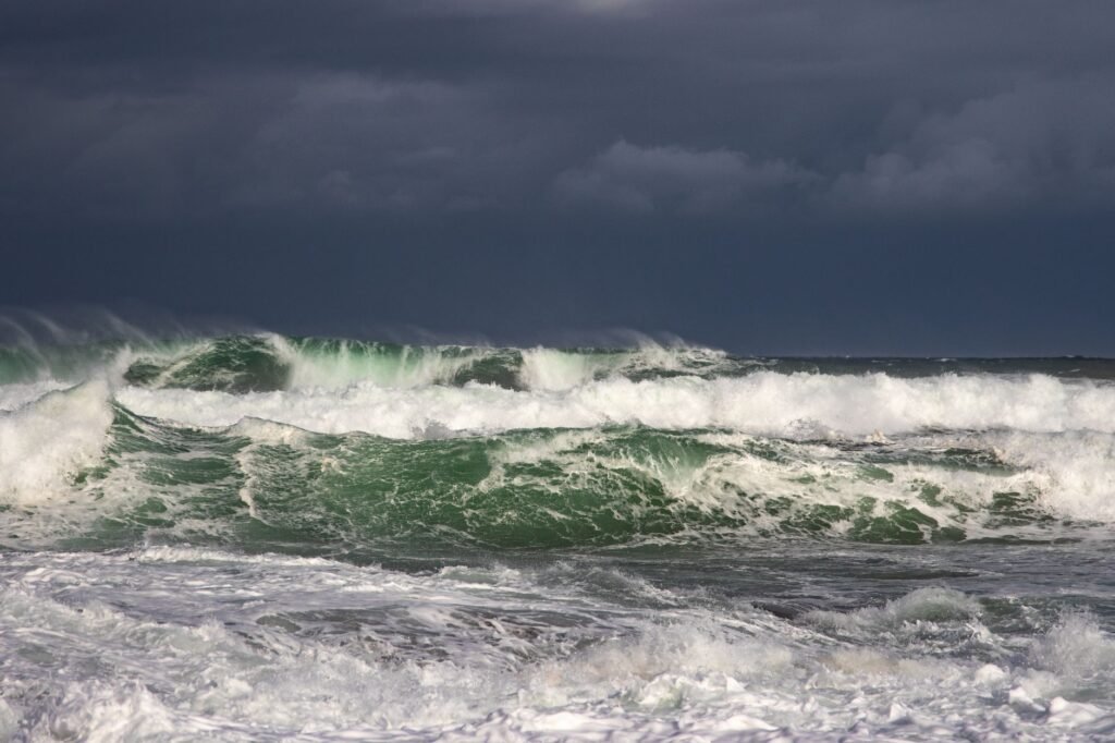 Dark gray storm clouds hanging low over a rough green sea with white breaking waves