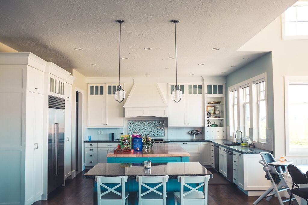 Bright white kitchen with a large island, pendant lights and a vent hood