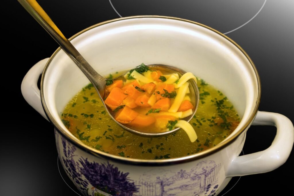 Warm chicken noodle soup with vegetables served in a decorative ceramic pot, perfect for a cozy winter meal
