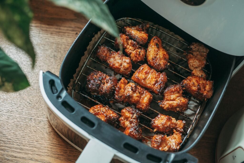 Seasoned chicken pieces cooked golden brown in an open air fryer basket on a table
