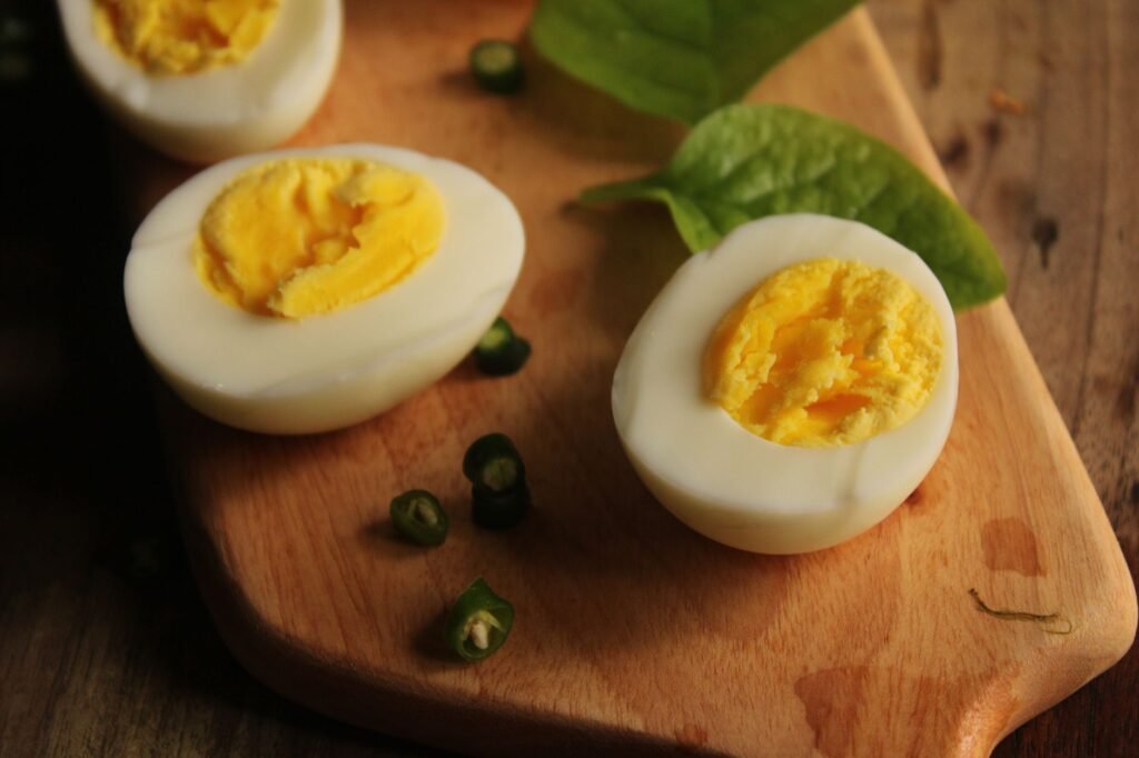Hard boiled eggs cut in half with bright yellow yolks on a wooden board