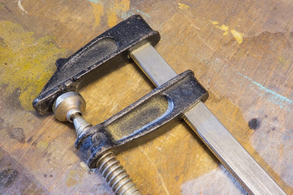 Metal bar clamp lying on a paint stained wooden work surface