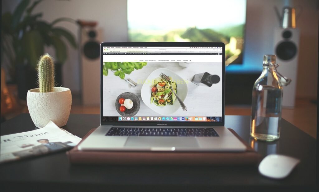 Laptop on a desk showing a web page in a browser beside a small cactus