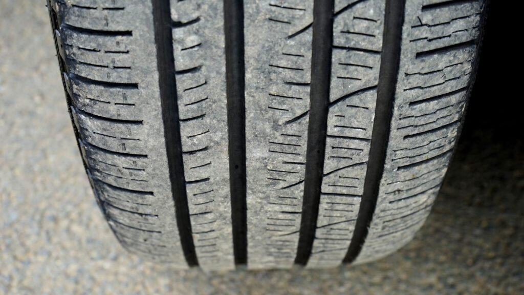 Close view of a car tire tread with deep straight grooves resting on pavement