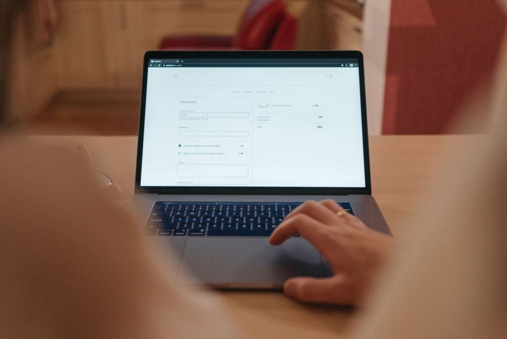 Person browsing a web page on an open laptop at a wooden table
