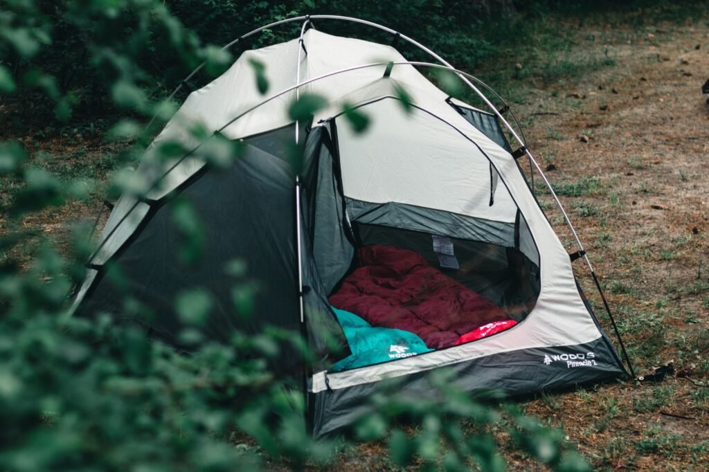 Small dome tent in a forest with a red sleeping bag visible through the open door