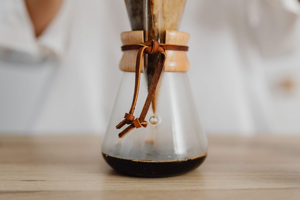 A detailed view of a Chemex coffee maker with freshly brewed drip coffee on a wooden surface