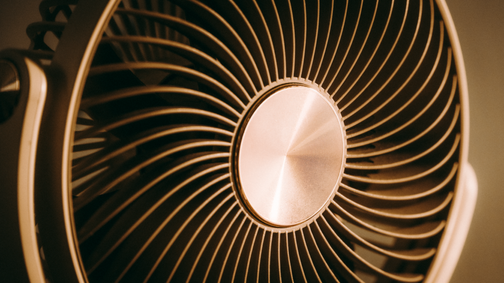 Close up of a table fan with a curved metal grille and a copper center hub