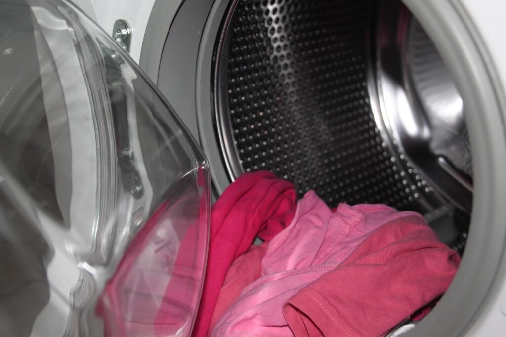Pink fabric loaded inside the stainless steel drum of an open washing machine