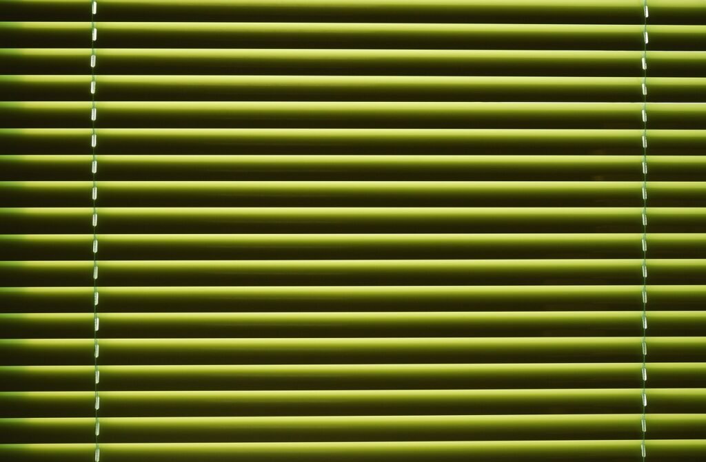 Close view of green horizontal window blind slats with thin lift cords
