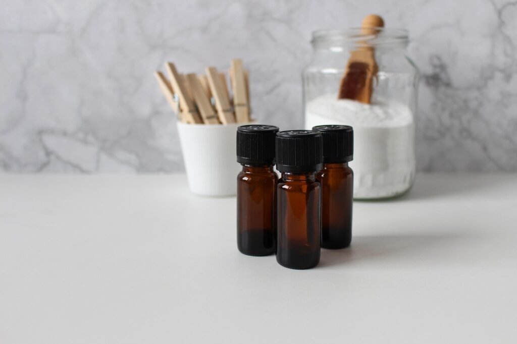 Glass jar of white powder with a wooden scoop beside small amber bottles and wooden sticks