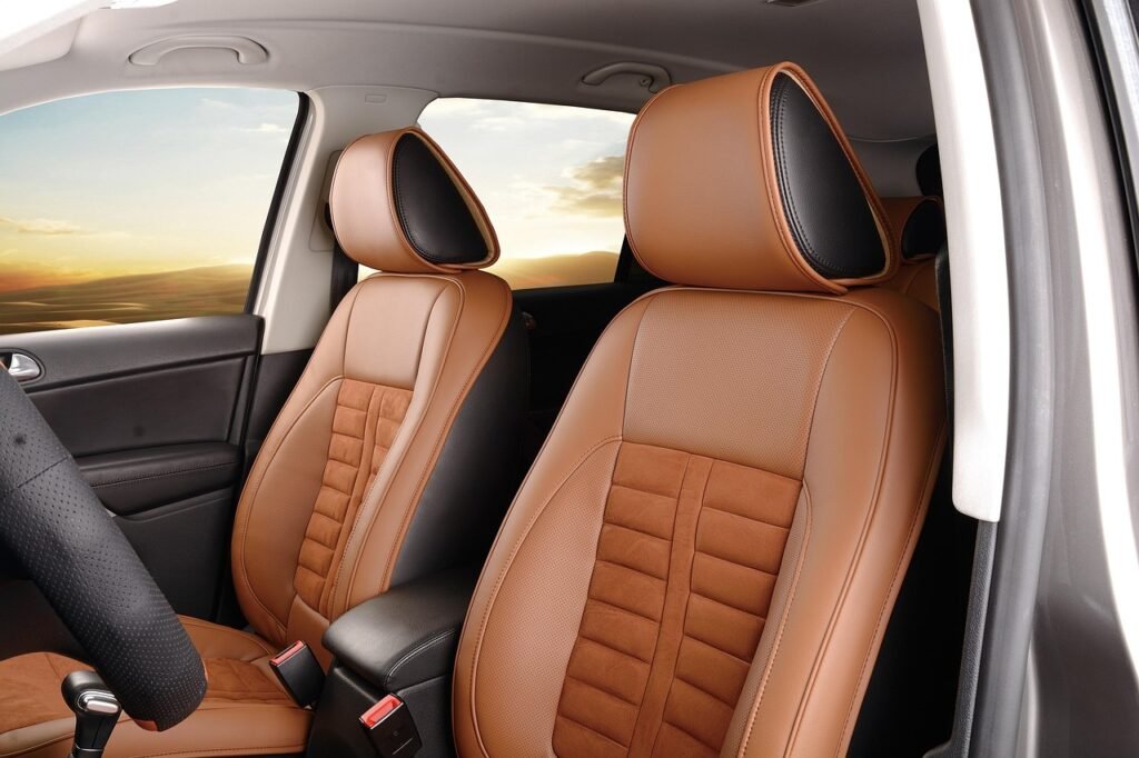 Tan leather front car seats with stitched centers lit by warm evening light