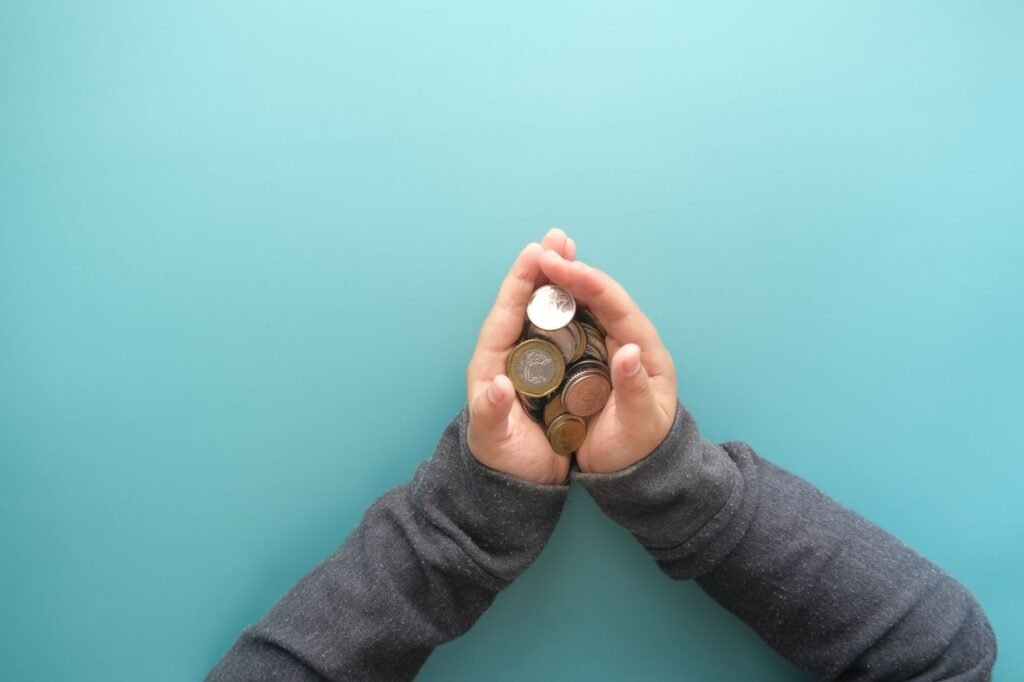 Two hands holding a stack of coins against a blue background, symbolizing savings or financial security