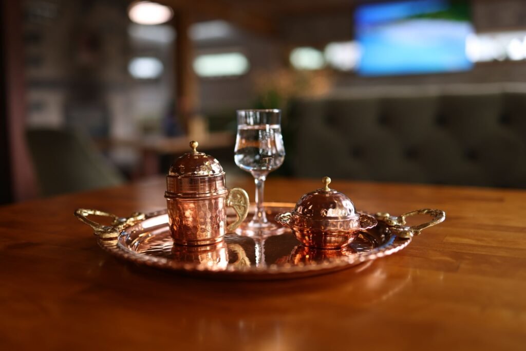 Elegant copper serving set with glass on a wooden table, perfect for indoor dining decor