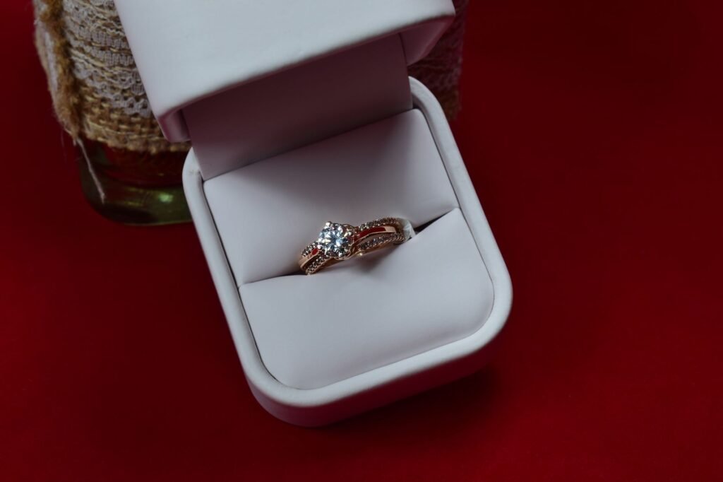 Close-up of a diamond ring in a white jewelry box against a red background, highlighting elegance and luxury